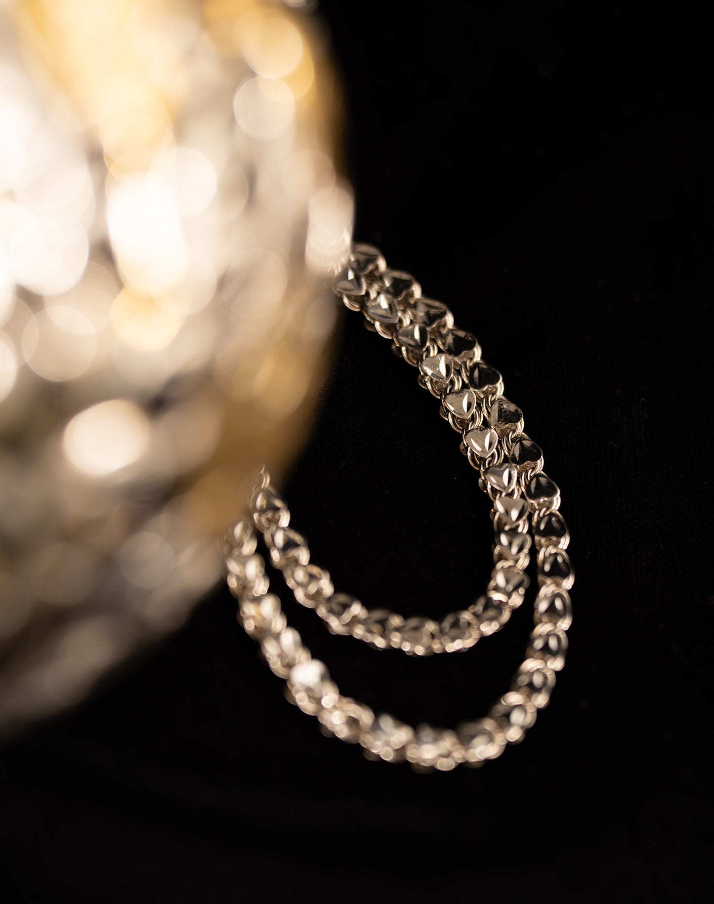 Close-up of a silver hoop chain with handmade brass cutwork and custom top clasp on the Daira luxury handbag.