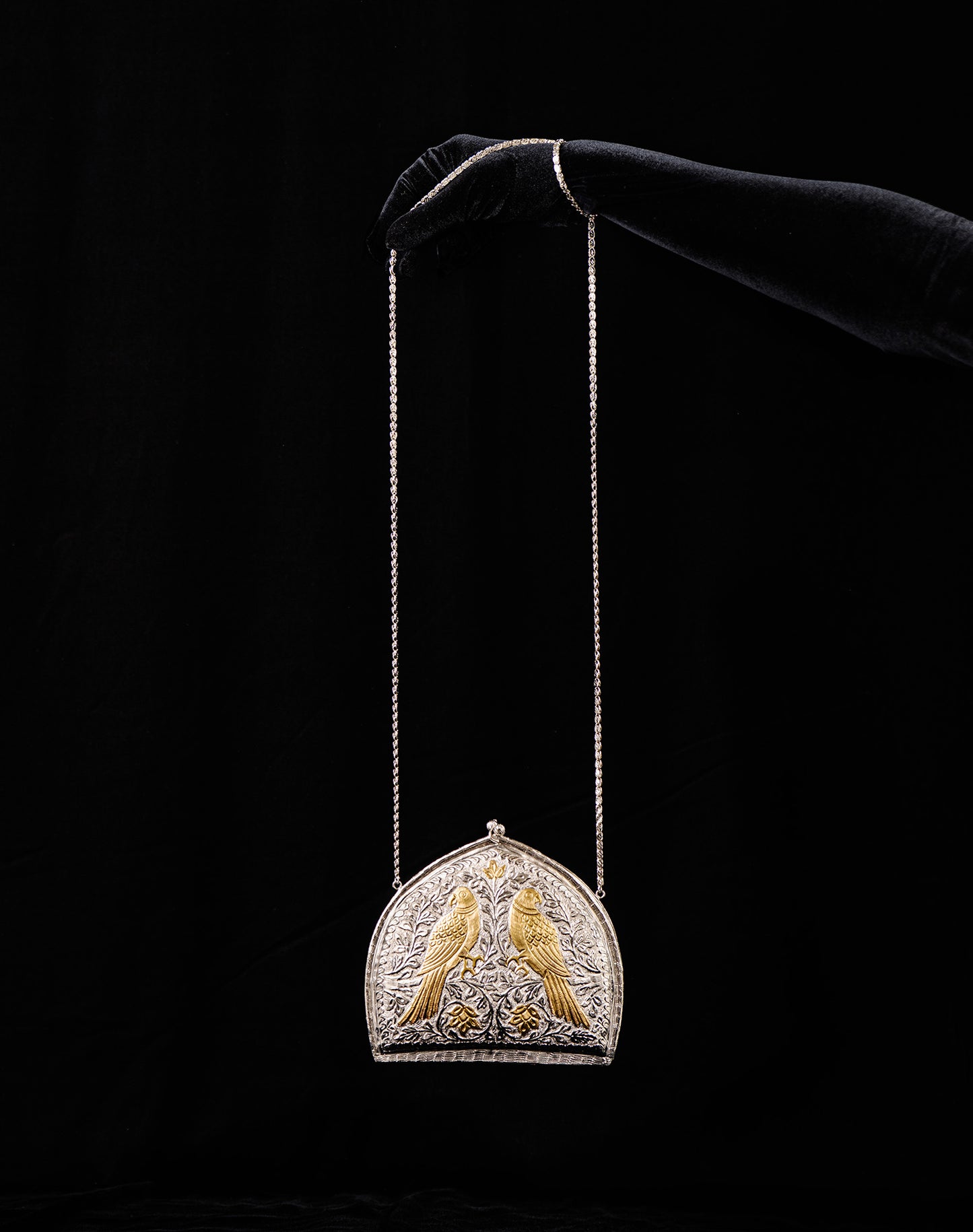 Decorative bag with two birds on a chain against a black background