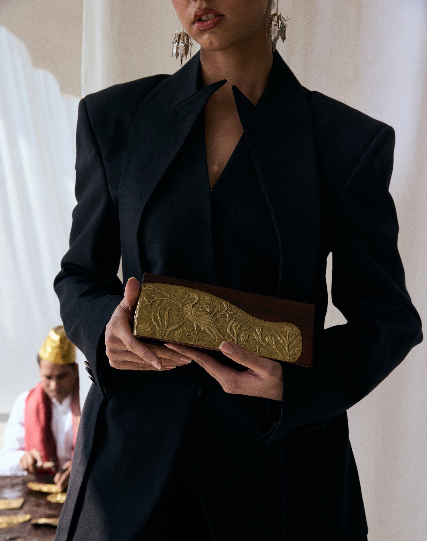 A model holding a gold Kunj handcrafted brass panel with carved sheesham wood body.