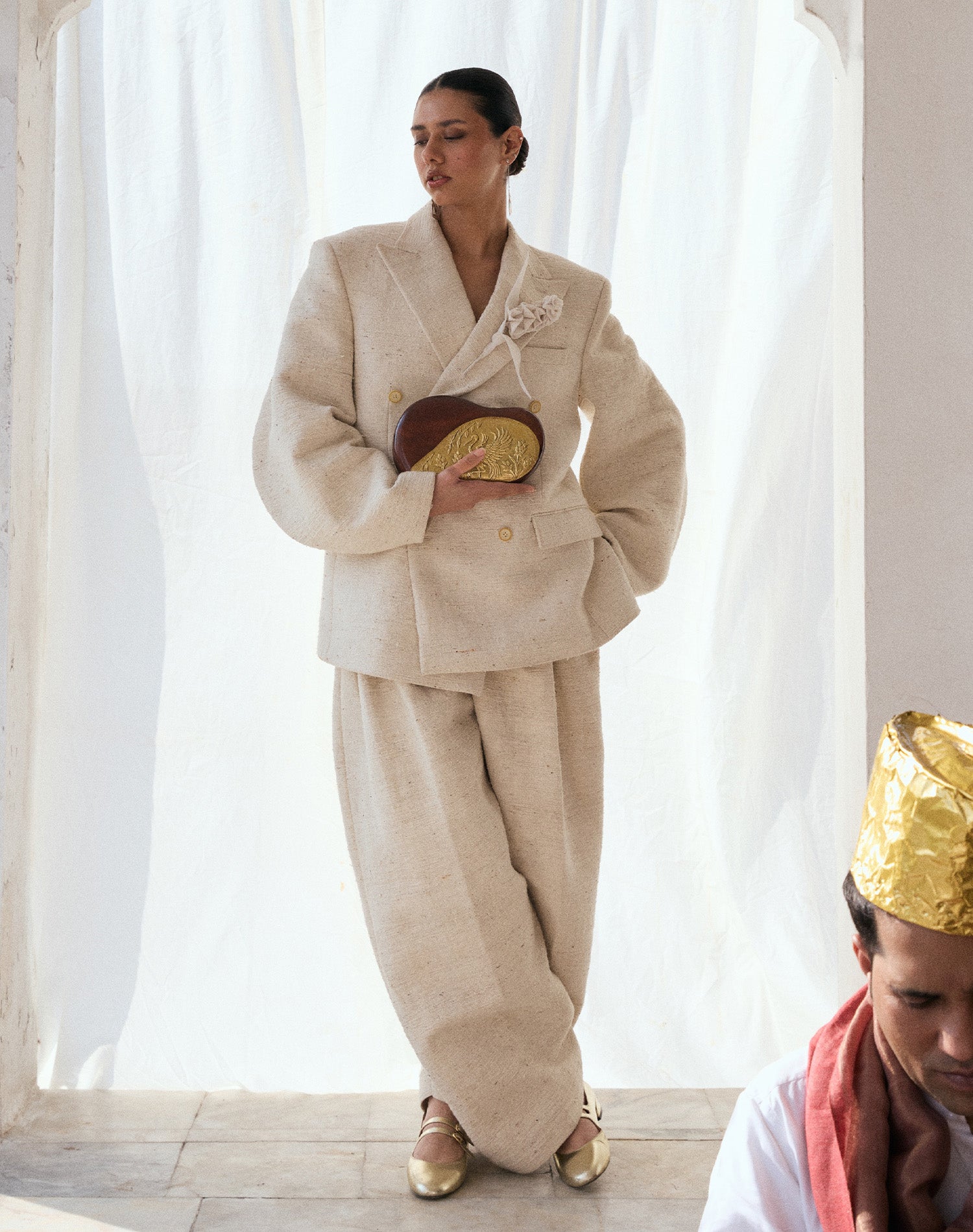 A model holding a luxury Sang bag in carved sheesham wood with brass accents with.