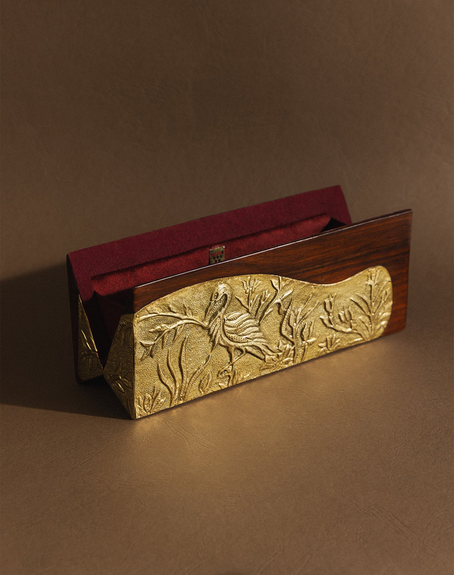 Decorative gold plaque with a parrot design on a wooden stand against a brown background