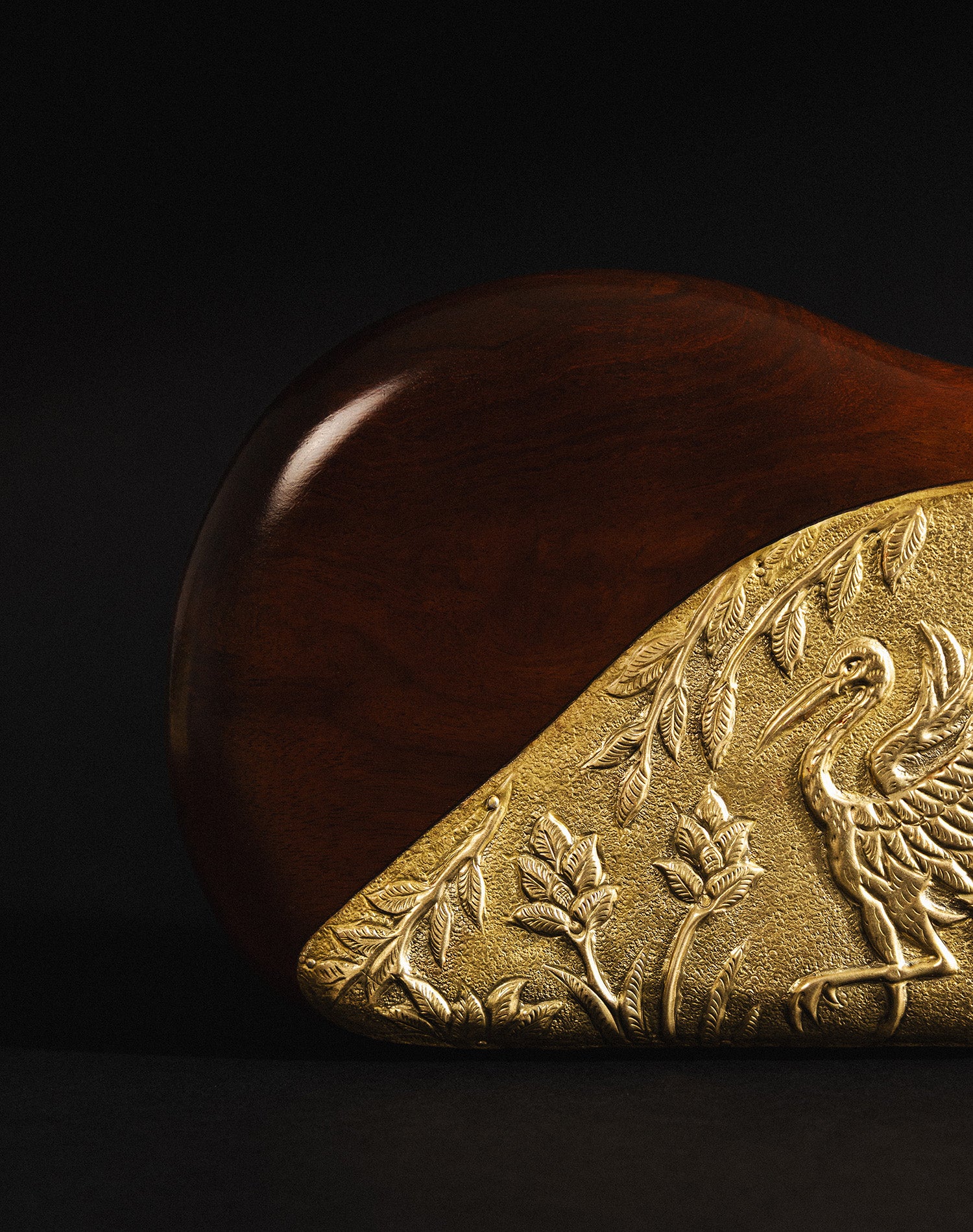 Gold embossed bag with bird and floral design.
Close-up of Sang bag showing brass detailing and velvet interior