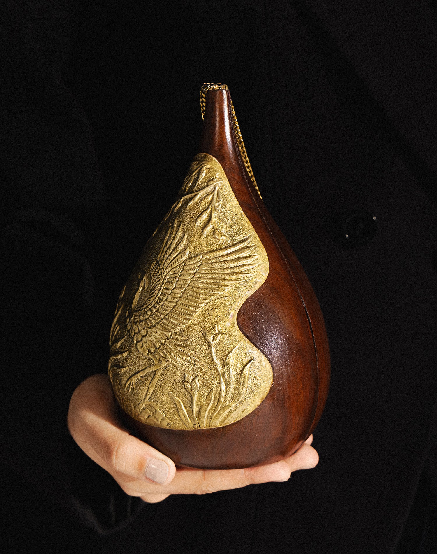 Model holding the Aab Bag wooden intricate  clutch with gold chain strap, showcasing its 6.5-inch length.