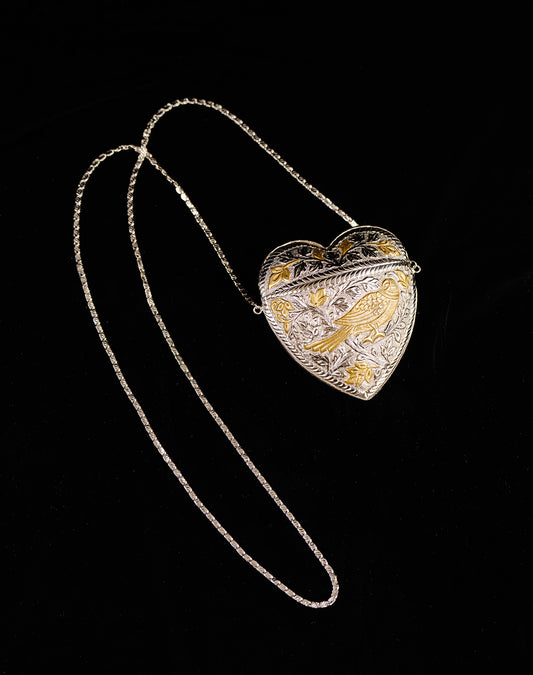Heart-shaped pendant bag with engraved design on a black background