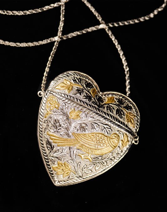 Dil Bag: Handcrafted heart-shaped intricate brass clutch with silver and gold plating, featuring intricate bird and floral engravings.
